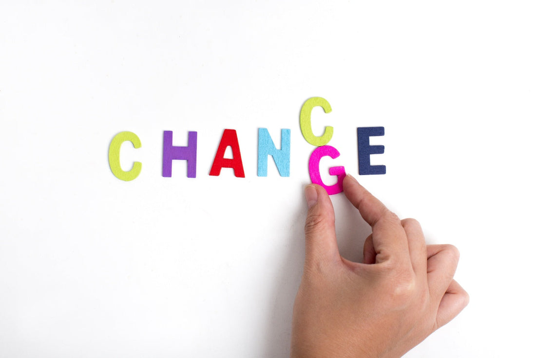 Colorful letters spelling the word “CHANGE” with a hand adjusting the last letter