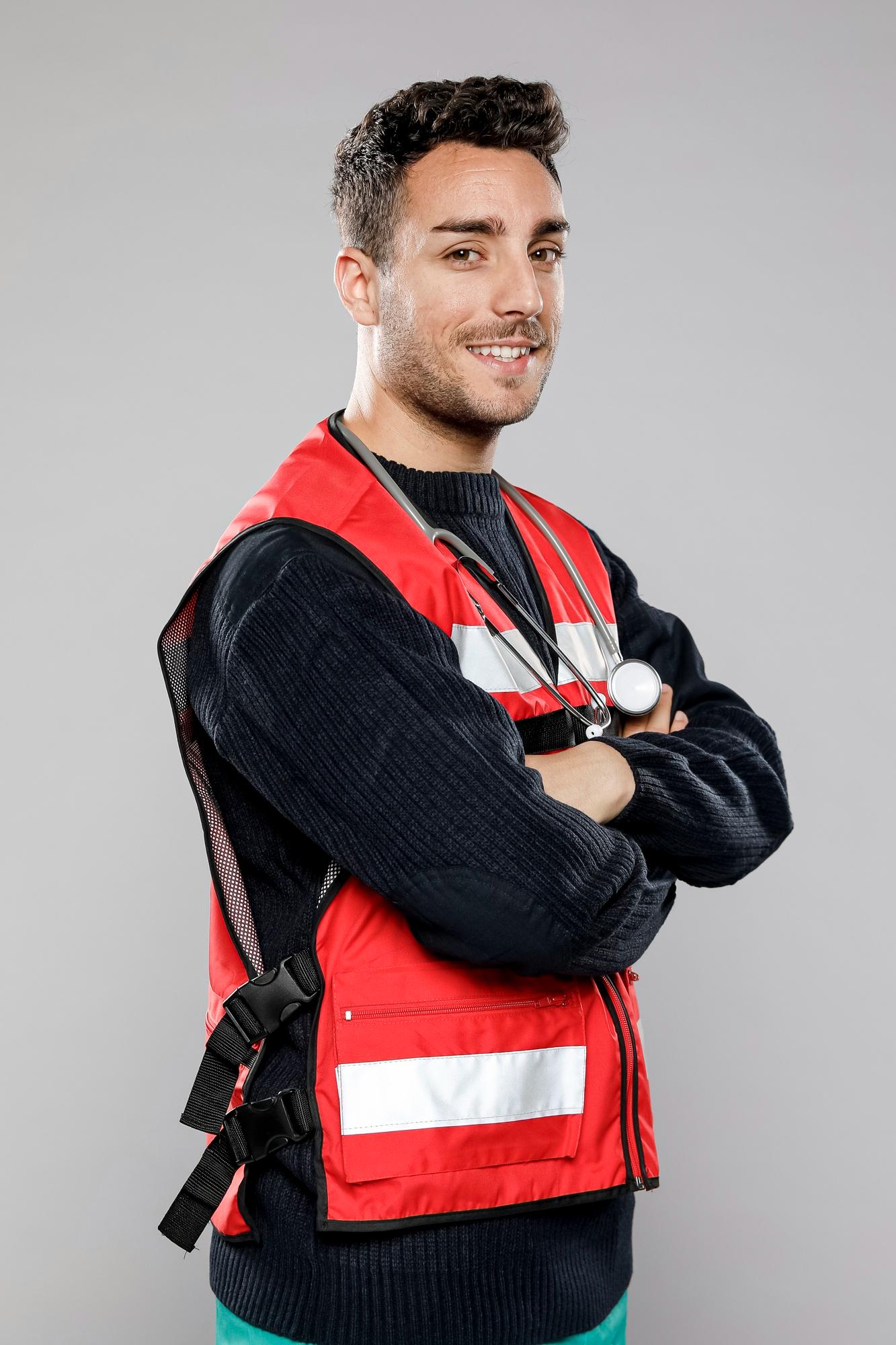 Male paramedic standing outdoors in uniform, smiling