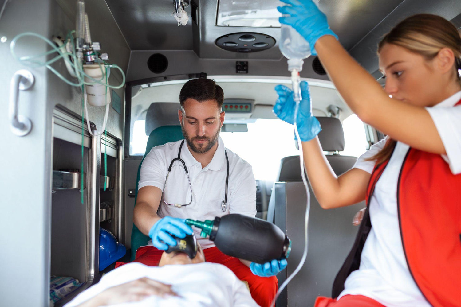 Two emergency medical technicians provide emergency care to a patient 