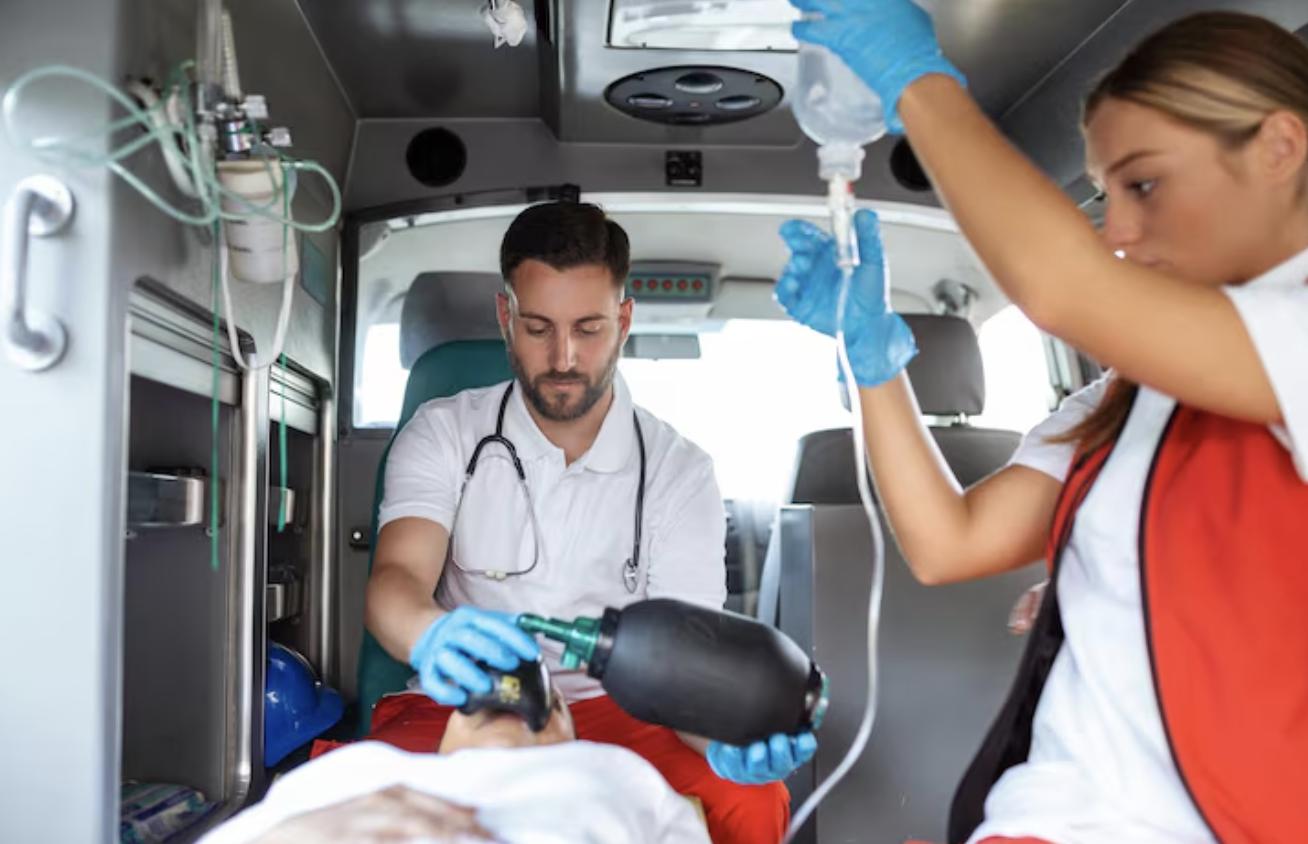 EMTs assisting a patient on a stretcher inside the back of an ambulance