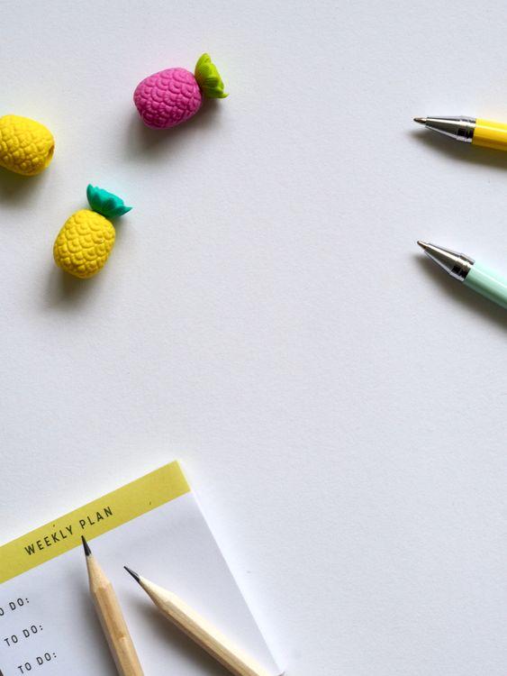 Flat lay of colorful pens, erasers, and a weekly planner on white background