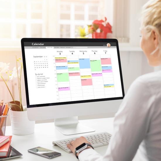 A person viewing a digital calendar on a computer screen, organizing their study schedule.