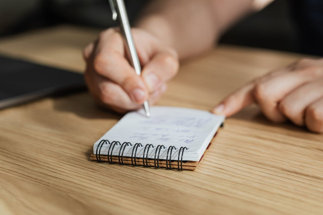 A person taking notes in a diary while studying for the NREMT exam.