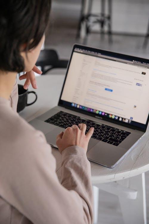 Person typing on a laptop at home, reviewing study materials for NREMT exam prep