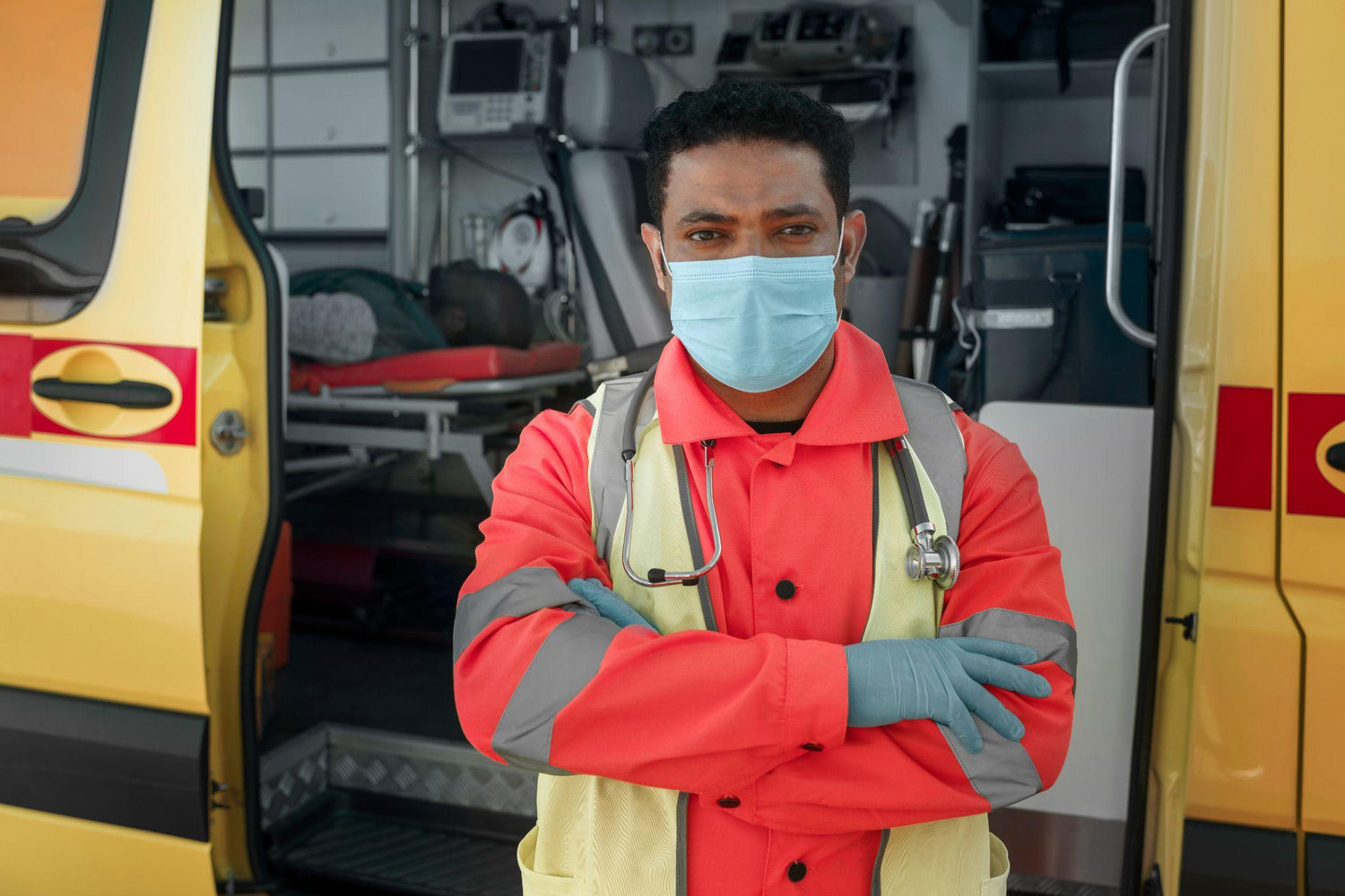 Paramedic standing in front of an ambulance with arms crossed