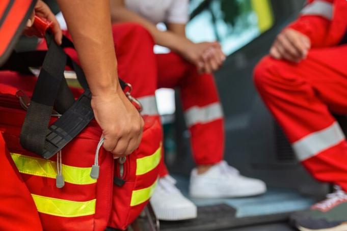 Paramedic standing at the rear of an ambulance, preparing to respond to an emergency call