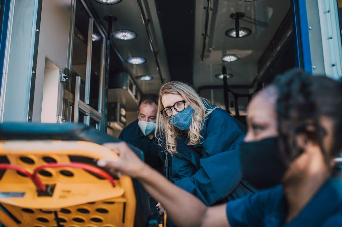 Two paramedics working together inside an ambulance, preparing equipment and monitoring patient care