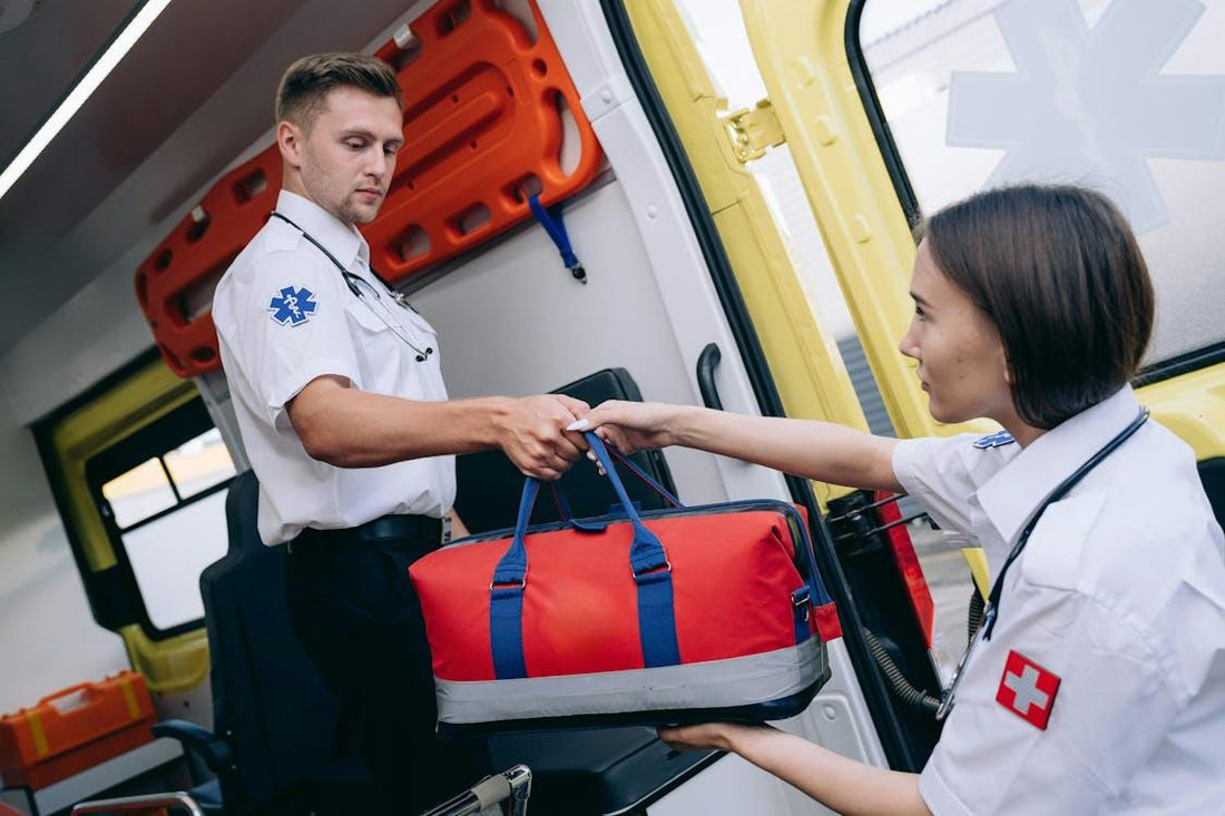 Two paramedics holding a medical bag inside an ambulance, readying equipment for patient care