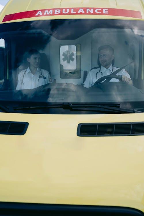 Paramedics working inside an ambulance cabin, preparing equipment and assessing a patient during an emergency response