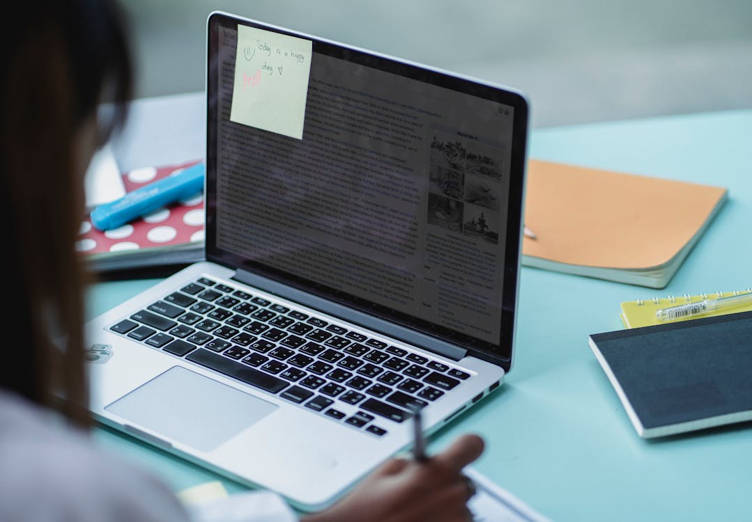 Students using a laptop and studying at a table with notebooks and papers