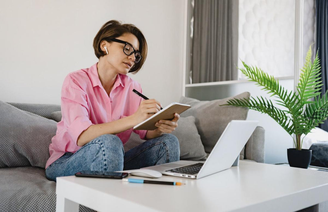 A woman studying for NREMT exam at home with notes and laptop