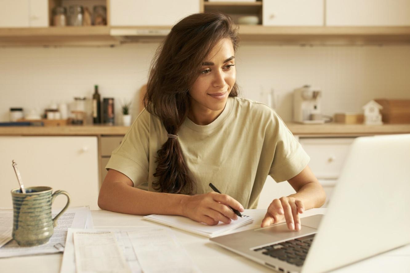 A young woman focused on her notes while studying in a comfortable home environment.