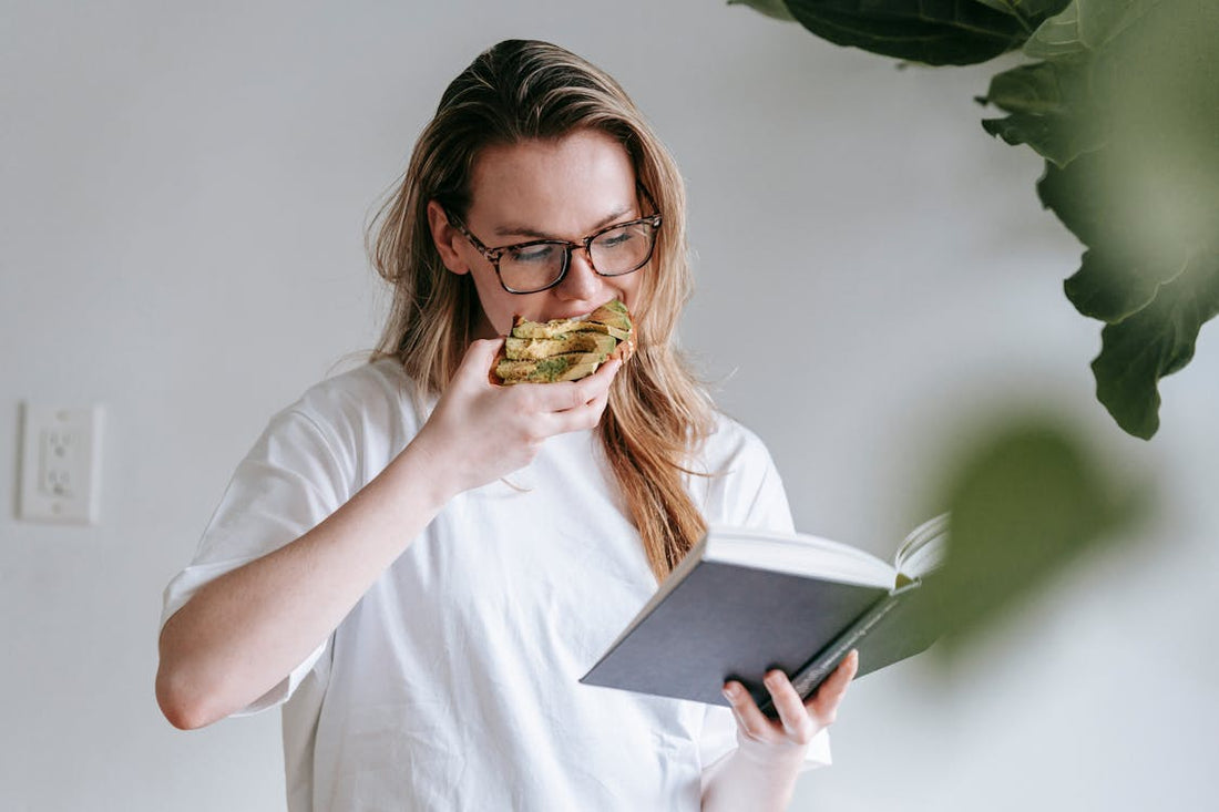 Young woman with a book and toast, preparing for her studies.